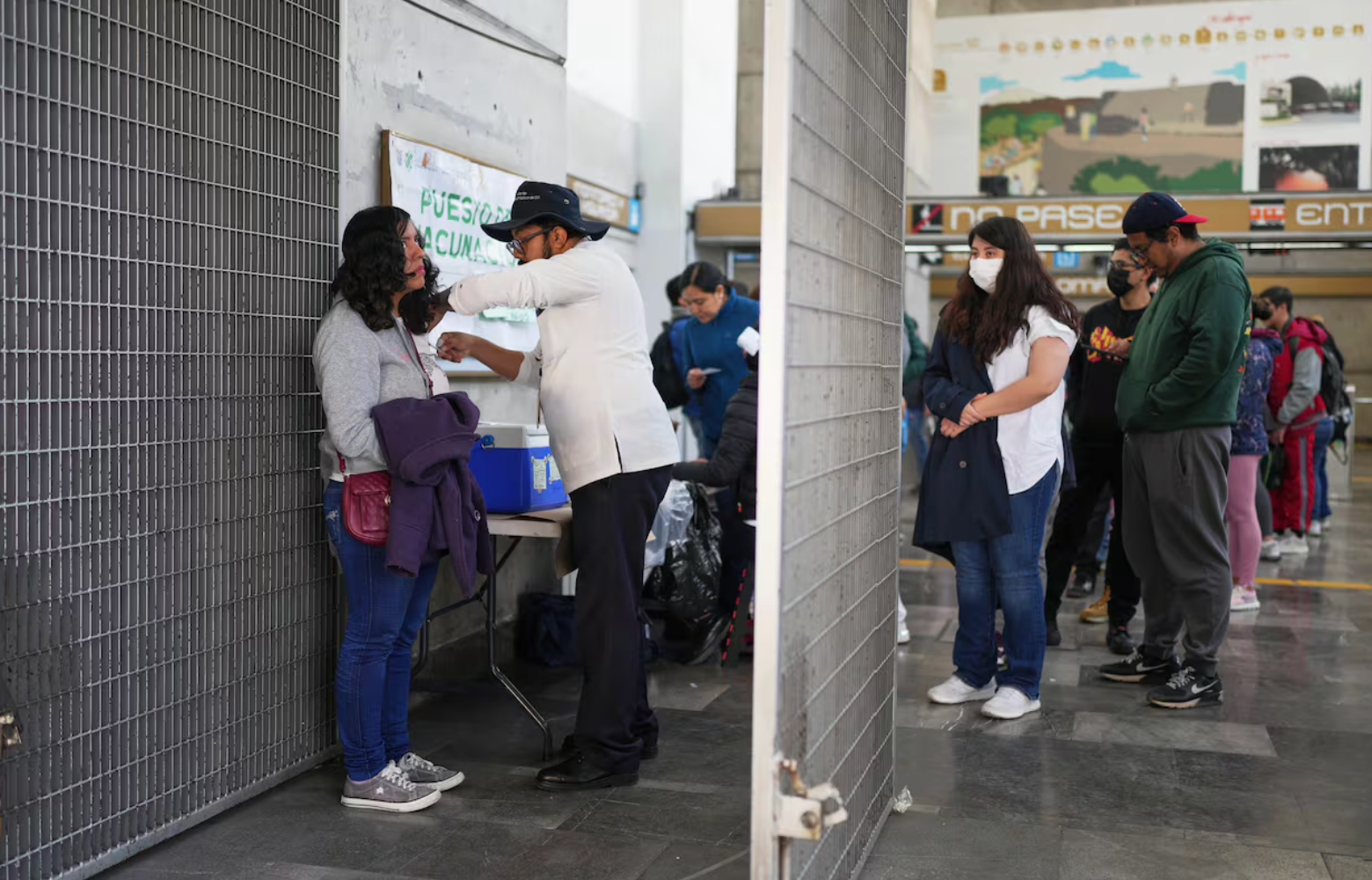 People  line up at a vaccination station. 